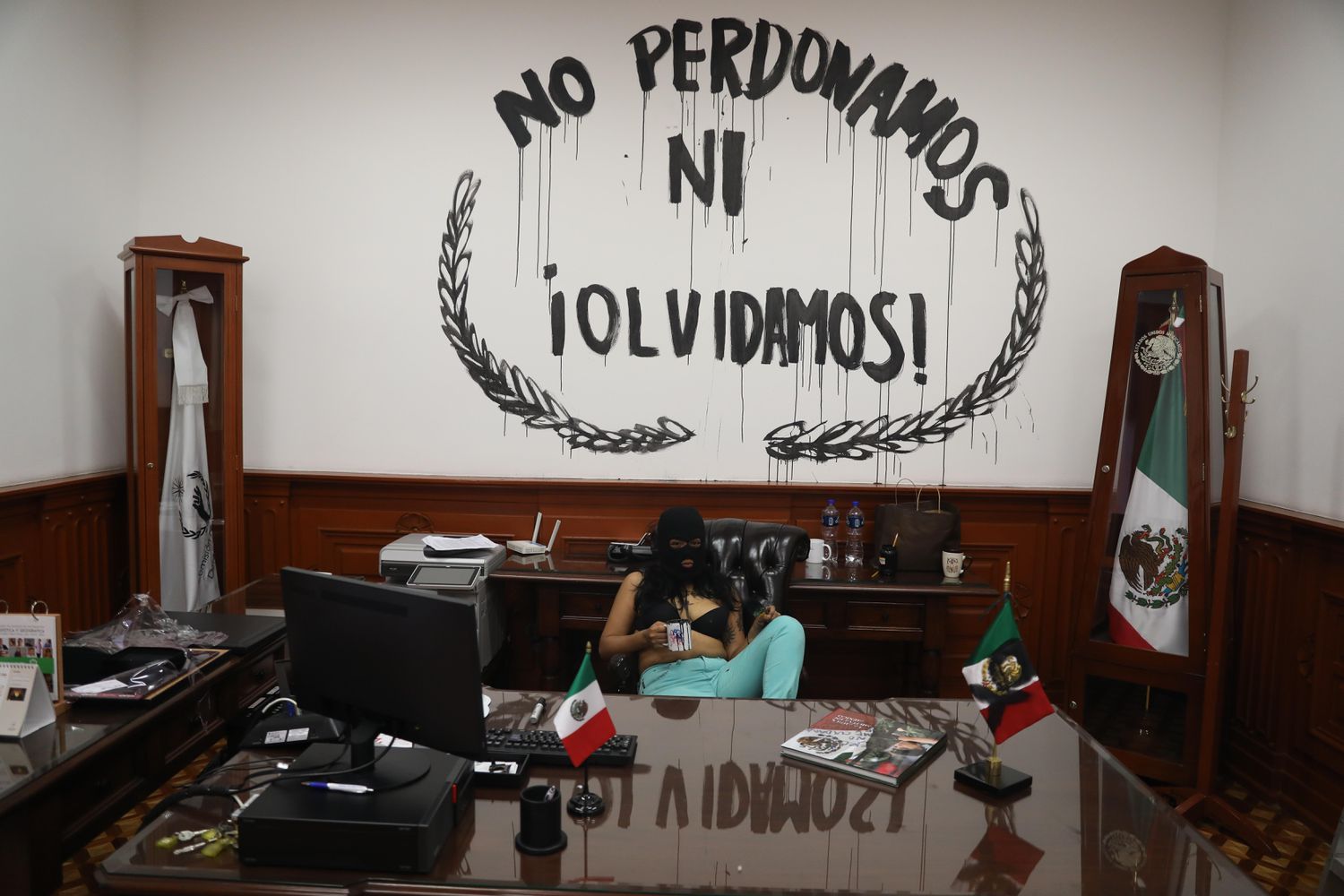 An activist inside the feminist occupied CNDH headquarters against the backdrop of spray painted words that read, “we do not forgive or forget.” Photo: El País.